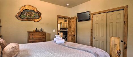 A bedroom with a large bed, a wooden headboard, a television mounted on the wall, and a wooden door.