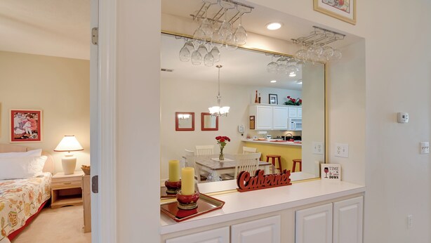 A hotel room with a bed, bedside table, lamp, and a mirror above the counter. - Cozy Condo w/ Golf Course View: 4 Mi to Shore! (Myrtle Beach)