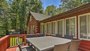 Une cabane en bois dotée d’une terrasse, de grandes fenêtres et de mobilier d’extérieur.