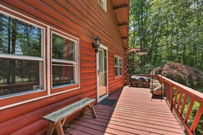 Eine Holzhütte mit einer Terrasse, großen Fenstern und Blick auf den Wald.