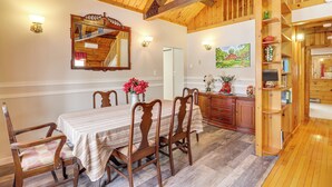 Un coin repas avec une table et des chaises en bois, un miroir, des appliques murales et un tableau.