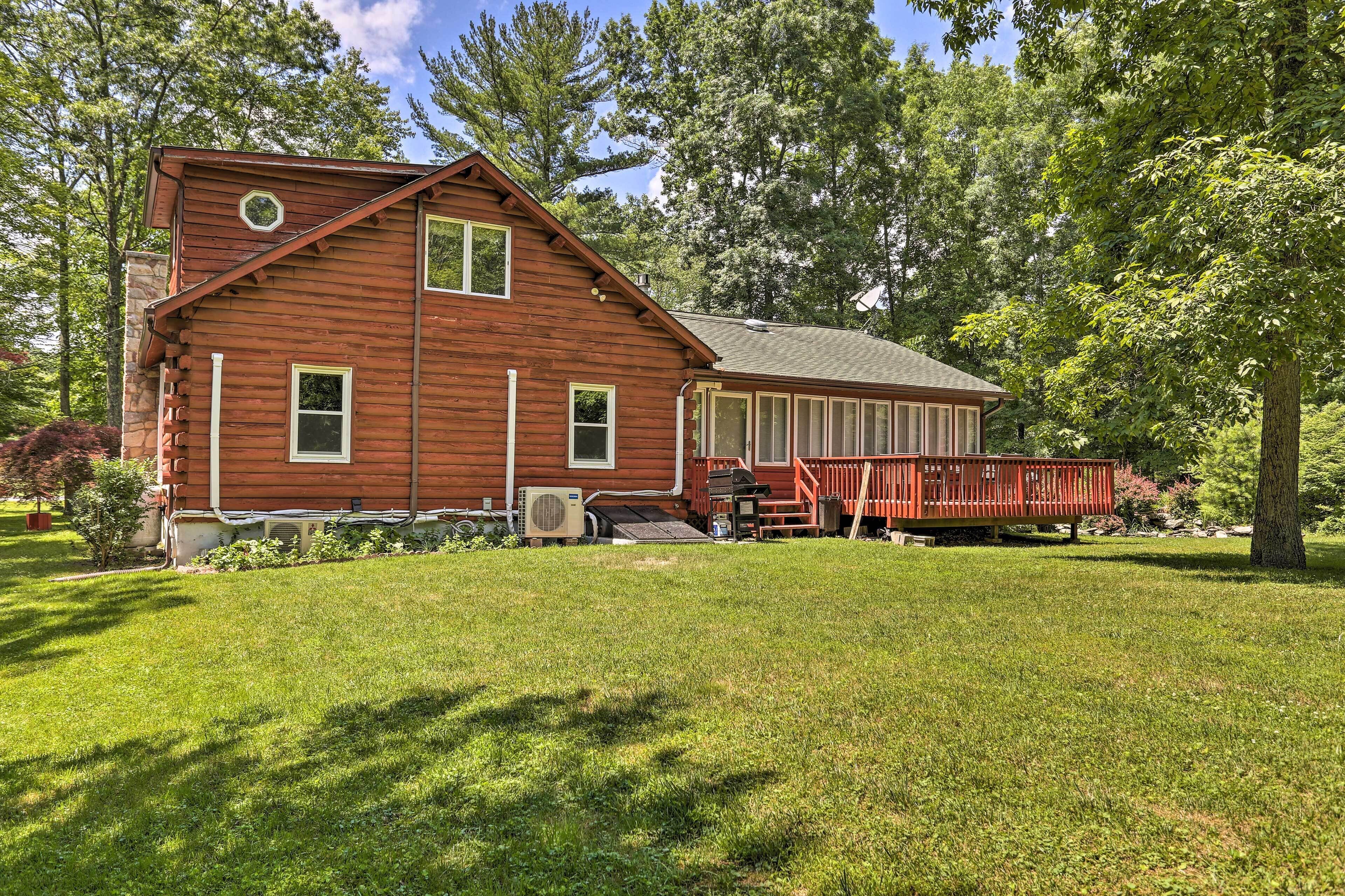 A rustic log cabin with a porch, surrounded by a well-maintained lawn and trees.