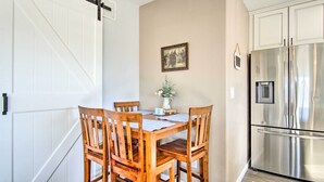 A dining area with a wooden table and chairs, a white door with a black handle, a framed picture on the wall, and a stainless steel refrigerator. - Tucson Vacation Rental ~ 5 Mi to Nat'l Park (Tucson)