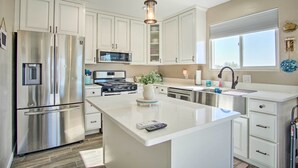 A modern kitchen with white cabinets, stainless steel appliances, a central island, and a pendant light. - Tucson Vacation Rental ~ 5 Mi to Nat'l Park (Tucson)