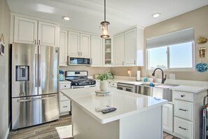 A modern kitchen with white cabinets, stainless steel appliances, a central island, and a pendant light. - Tucson Vacation Rental ~ 5 Mi to Nat'l Park (Tucson)