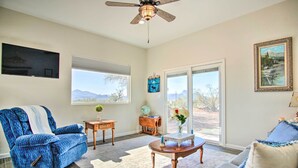 A living room with a blue sofa, a wooden coffee table, and a television mounted on the wall. - Tucson Vacation Rental ~ 5 Mi to Nat'l Park (Tucson)