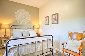 A neatly made bed with a headboard, two bedside lamps, a decorative wall piece, and a wooden chair with a cushion. - Tucson Vacation Rental ~ 5 Mi to Nat'l Park (Tucson)