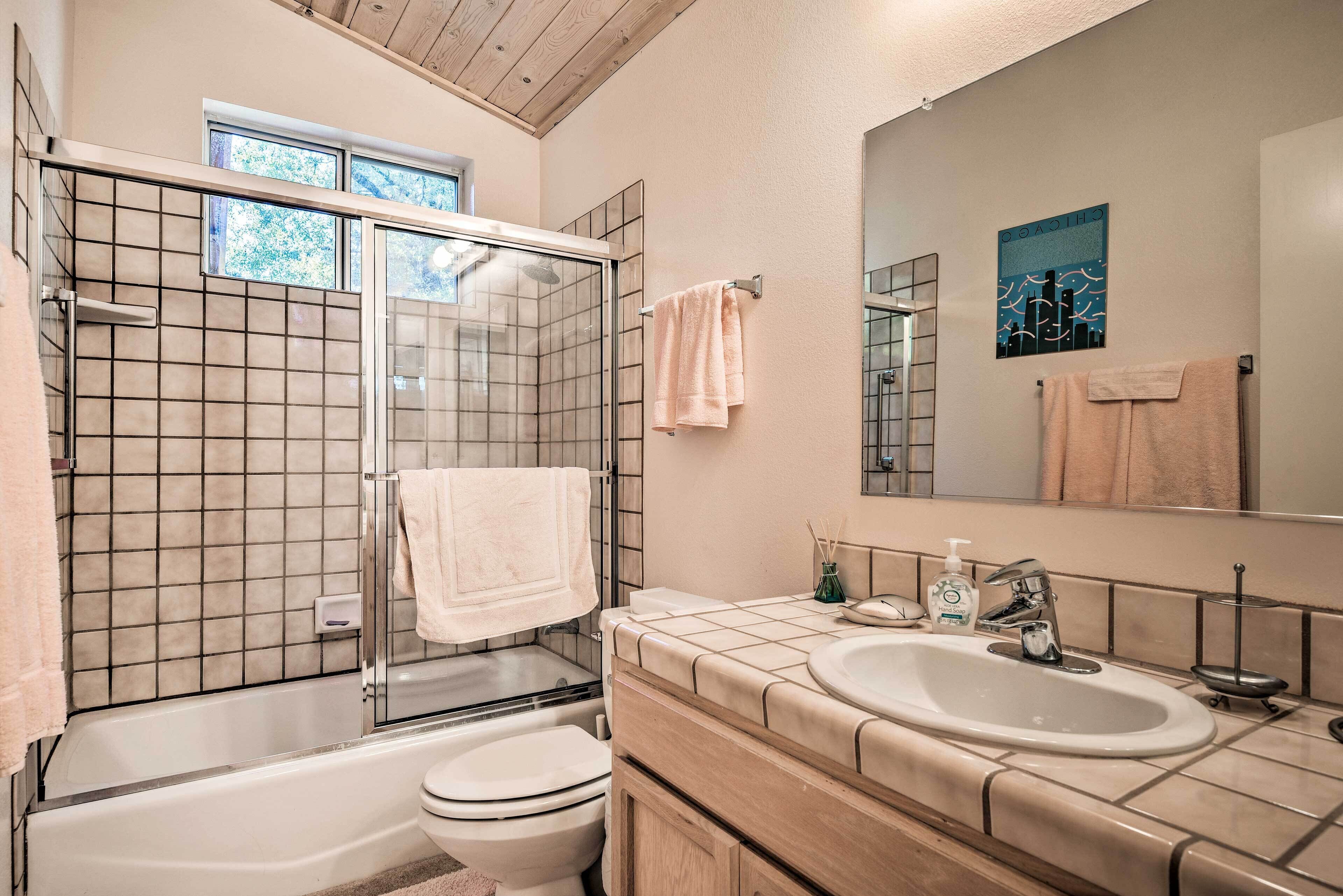 Un baño moderno con ducha envuelta en vidrio, inodoro, lavamanos y espejo.
