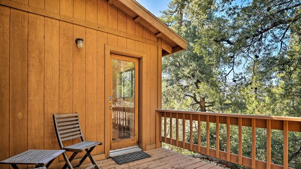 A wooden cabin with a porch, two wooden chairs, and a small table. - Pine Mountain Club Cottage W/wraparound Deck! (Pine Mountain Club)