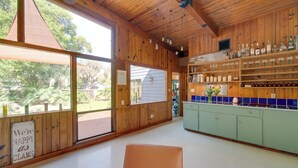 A wooden interior with a bar area, shelves with bottles, and a sign that reads "We're happy as clams." - 2 Mi to Riverwalk: Palmetto Gem w/ Fire Pit & BBQ (Palmetto)