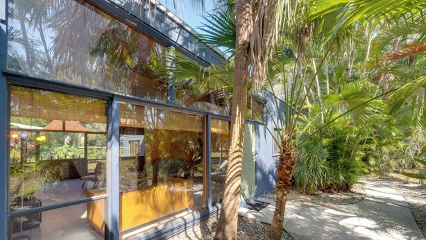A modern building with large glass windows reflecting the surrounding greenery. - 2 Mi to Riverwalk: Palmetto Gem w/ Fire Pit & BBQ (Palmetto)
