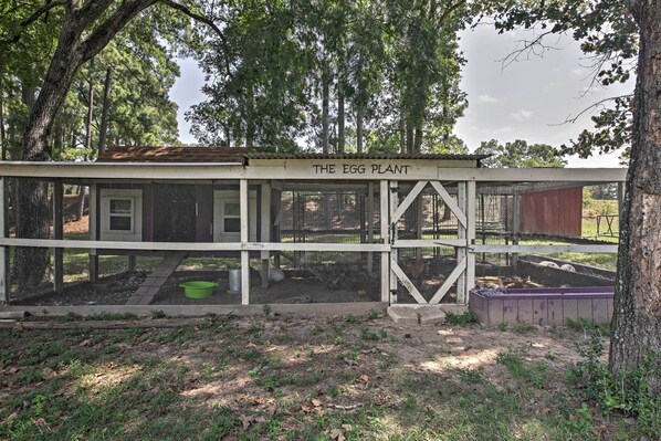 A rustic wooden structure labeled "The Egg Plant" with a fenced garden area and a small pond.