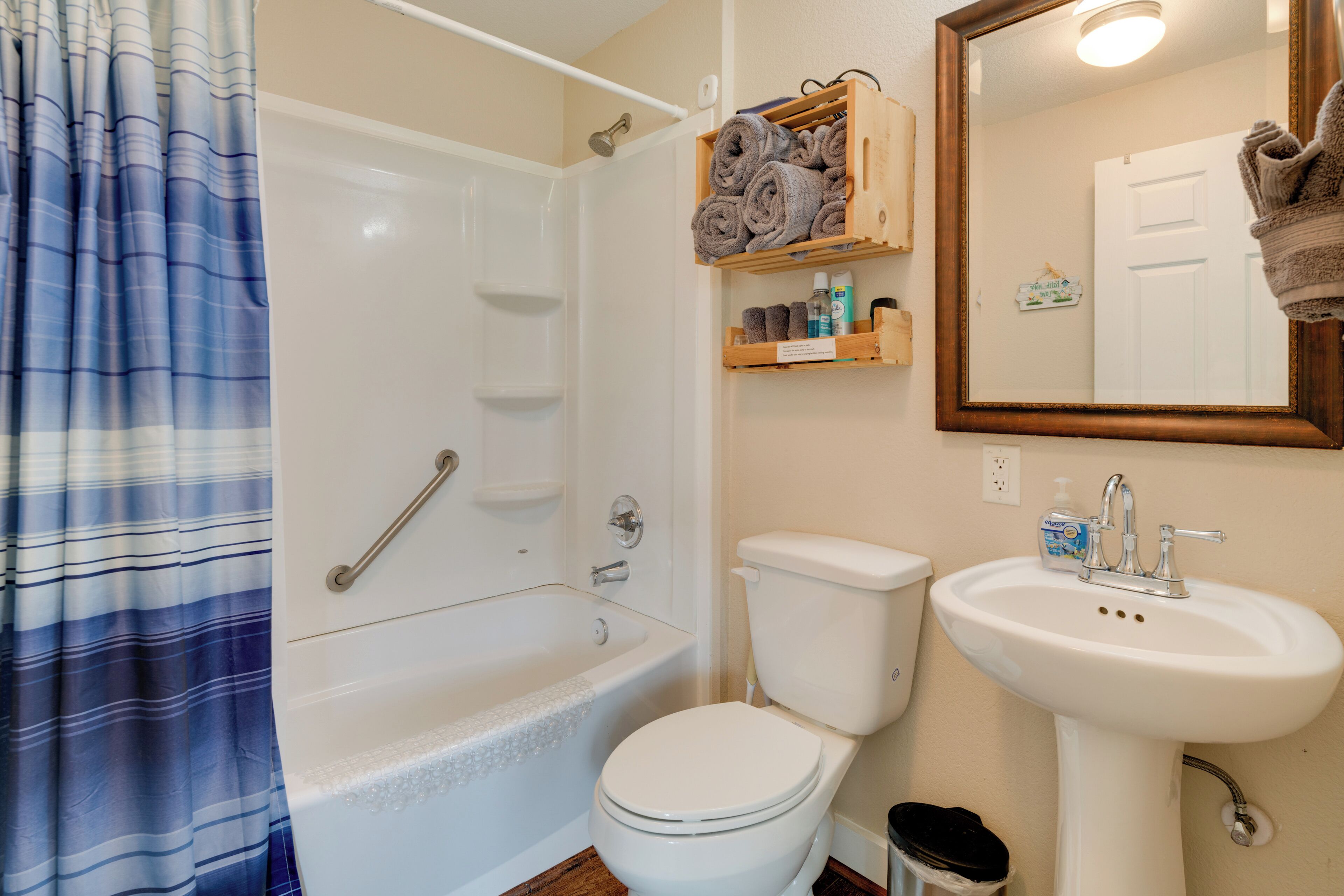 A bathroom with a bathtub, toilet, sink, and a mirror.
