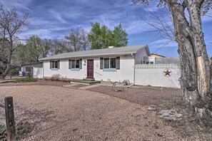 A single-story house with a front porch, a red door, and a white exterior. - Pet-friendly Canon City Home w/ Fenced Yard! (Canon City)