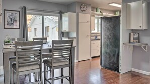 A modern kitchen with white cabinets, a dining area with two chairs, and a large window. - Pet-friendly Canon City Home w/ Fenced Yard! (Canon City)