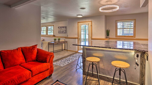 Une cuisine moderne avec un coin bar, un canapé rouge et un tapis à motifs.