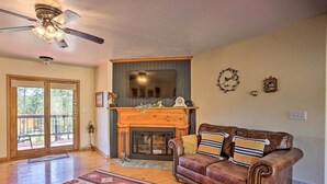 Un salon avec une cheminée, un canapé en cuir et un ventilateur de plafond.