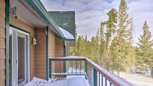 Un bâtiment en bois avec un porche vert et une terrasse recouverte de neige.