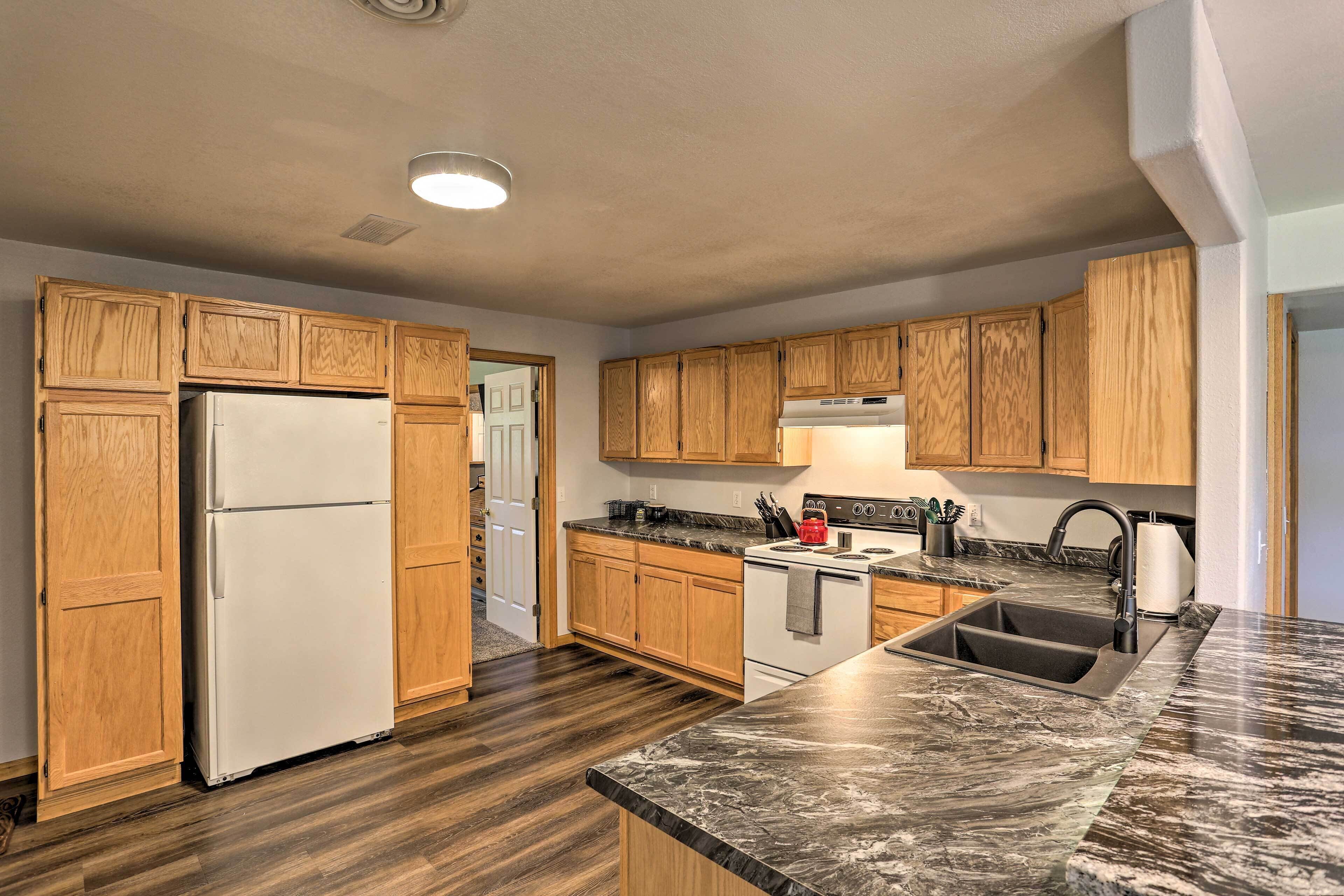 A kitchen with wooden cabinets, a white refrigerator, a stove, and a marble countertop.