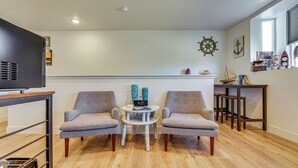 A modern living room with two grey armchairs, a small round table, wooden flooring, a mounted TV, and nautical decor. - Dtwn Walkability! Grand Junction Couple's Retreat (Grand Junction)