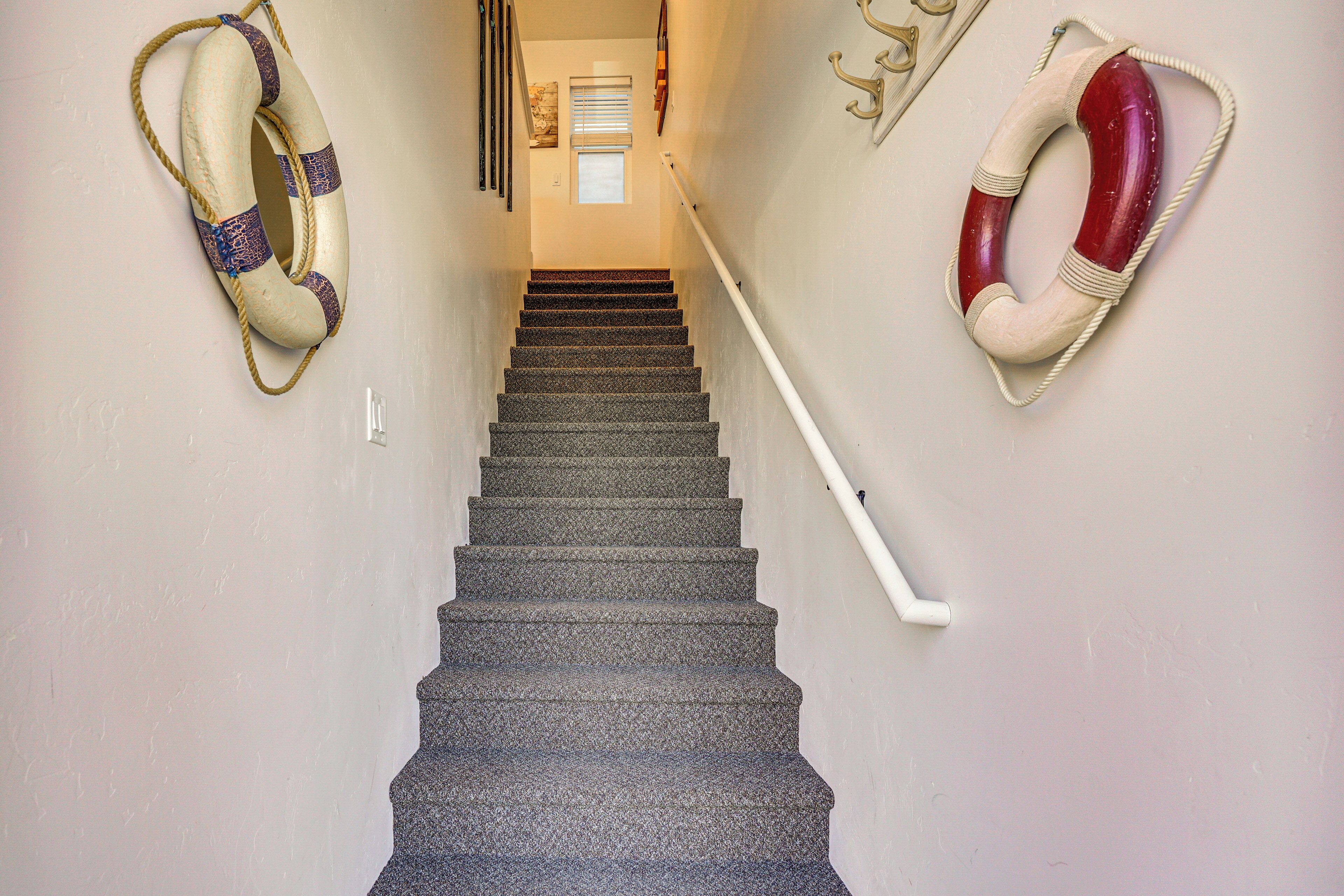 A staircase with a handrail, two life rings on the walls, and a window at the top.