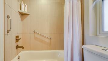 A bathroom with a bathtub, a shower with a grab bar, and a toilet.