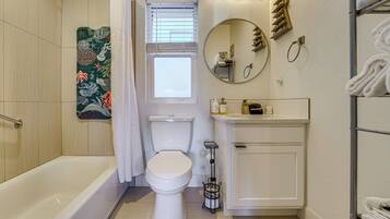 Une salle de bain avec une baignoire, des toilettes, un lavabo et un miroir.