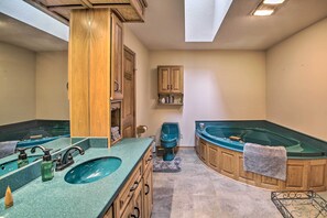 A bathroom with a large bathtub, a double sink vanity, and a wooden cabinet. - Spacious House w/ Wraparound Deck + Mtn Views! (Royal)