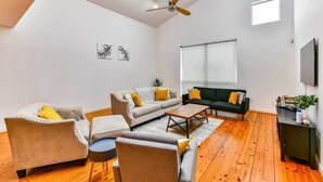 Uma sala de estar moderna com sofá, poltronas, mesa de centro e televisão.