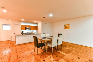 A modern kitchen with wooden cabinets, a microwave, and a dining area with a wooden table and chairs. - Modern Houston Townhome: 5 Miles to Downtown! (Houston)
