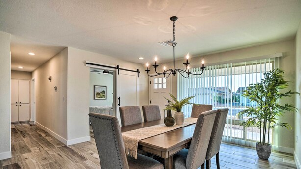 A dining area with a wooden table, upholstered chairs, a chandelier, and a potted plant.