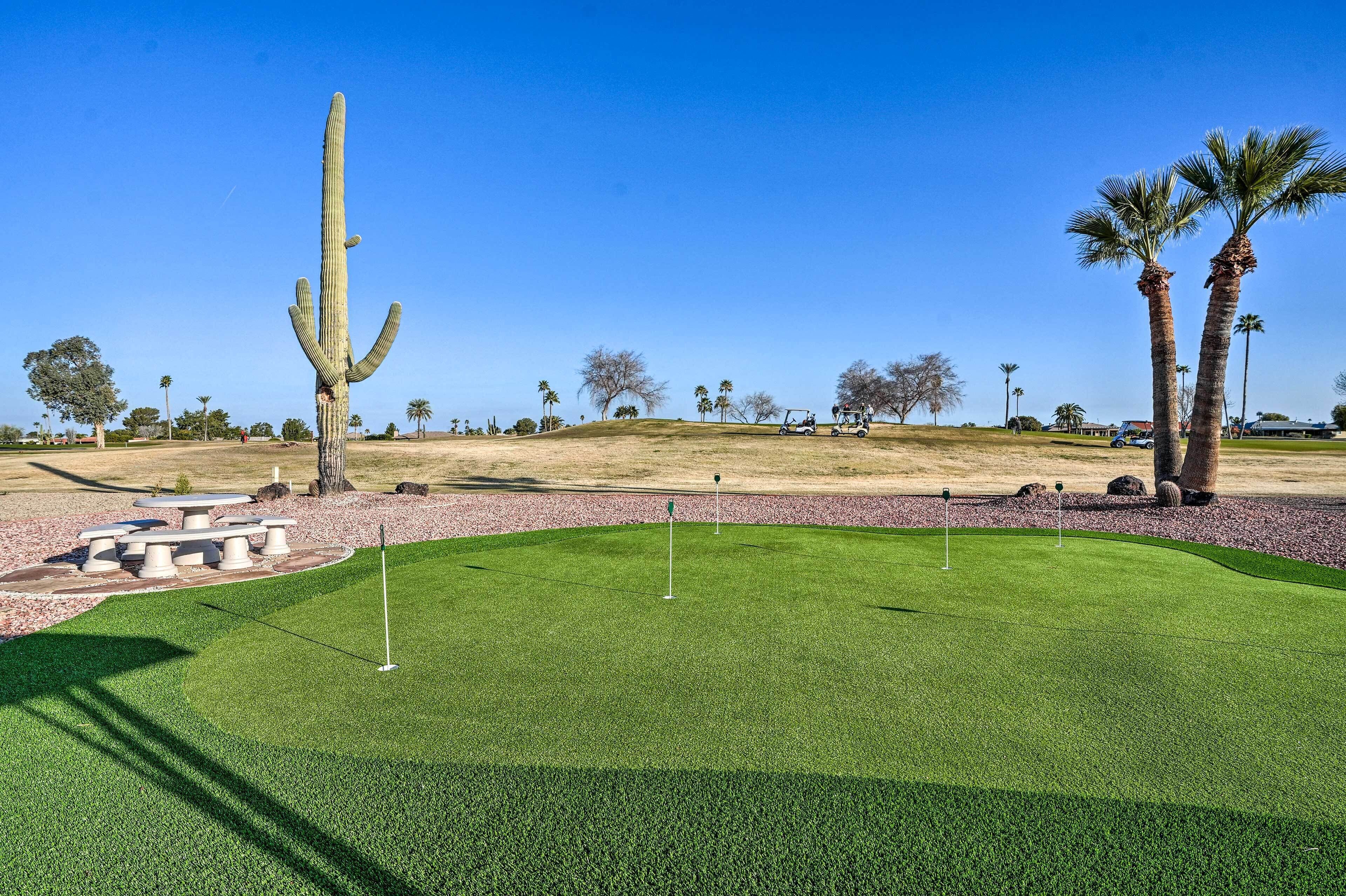 A golf course with a cactus, palm trees, and a picnic area.