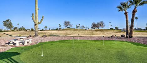 A golf course with a cactus, palm trees, and a picnic area.