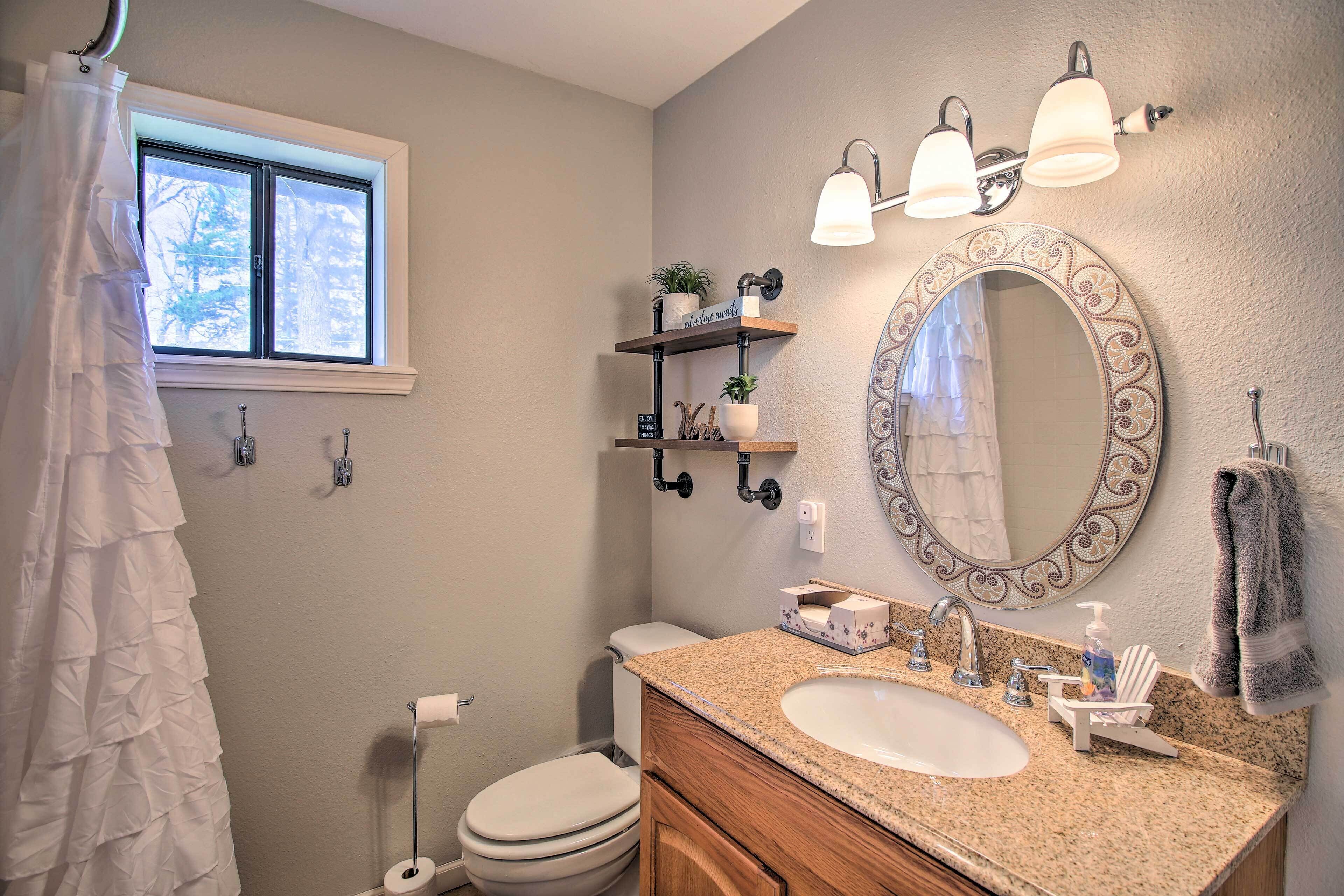 A bathroom with a toilet, sink, vanity, and a window.