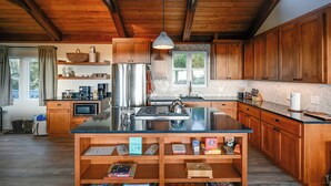 A spacious kitchen with wooden cabinets, a large island, and a view of the outdoors. - Hot Tub + Ocean Views: Spacious Irish Beach Home! (Manchester)