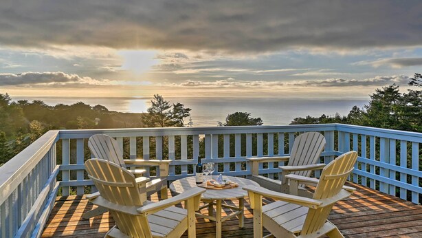 A deck with Adirondack chairs and a table, overlooking a body of water and trees. - Hot Tub + Ocean Views: Spacious Irish Beach Home! (Manchester)