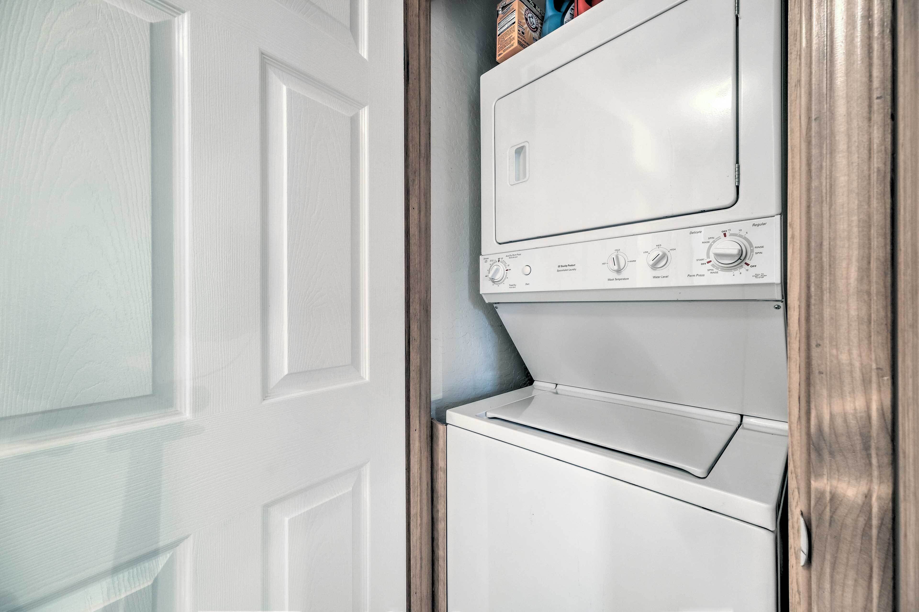 A white wall-mounted washer and dryer unit with control knobs and a small shelf above.