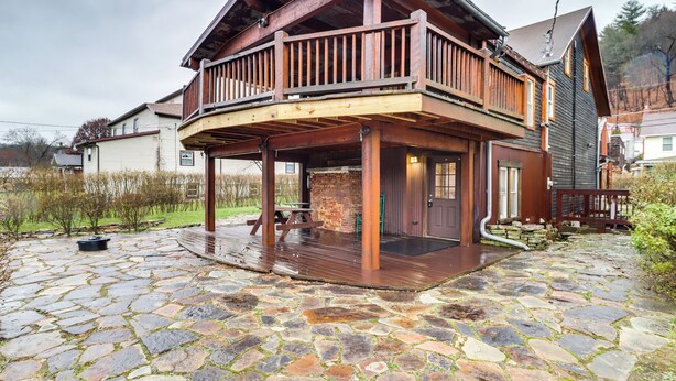 Een tweelaags huis met een houten terras en een stenen patio.