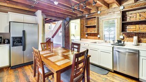 Een keuken met houten kastjes, een roestvrijstalen koelkast en een eettafel met stoelen.
