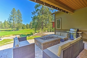 An outdoor patio with wicker furniture, a stone fire pit, and a grill.