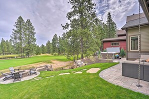 A backyard with a fire pit, outdoor seating, and a patio area.