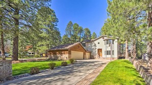 A two-story house with a garage, surrounded by a well-maintained lawn and tall pine trees. - Spacious Flagstaff Home w/ Hot Tub & Grill! (Flagstaff)