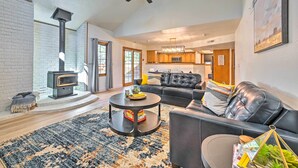 A modern living room with a fireplace, a black leather sofa, a coffee table, and a large rug. - Spacious Flagstaff Home w/ Hot Tub & Grill! (Flagstaff)