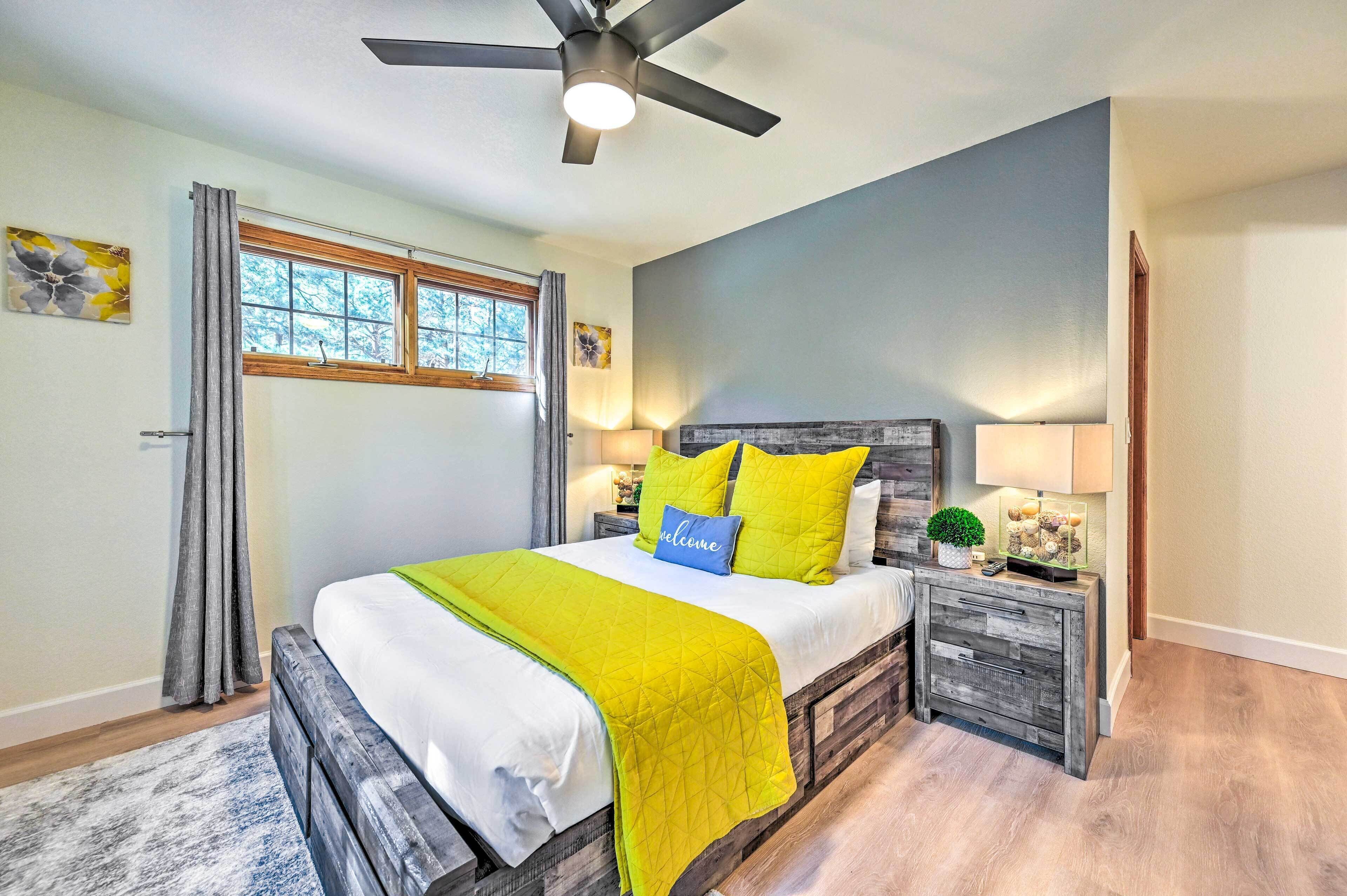 A bedroom with a bed, a ceiling fan, a nightstand, and a window.