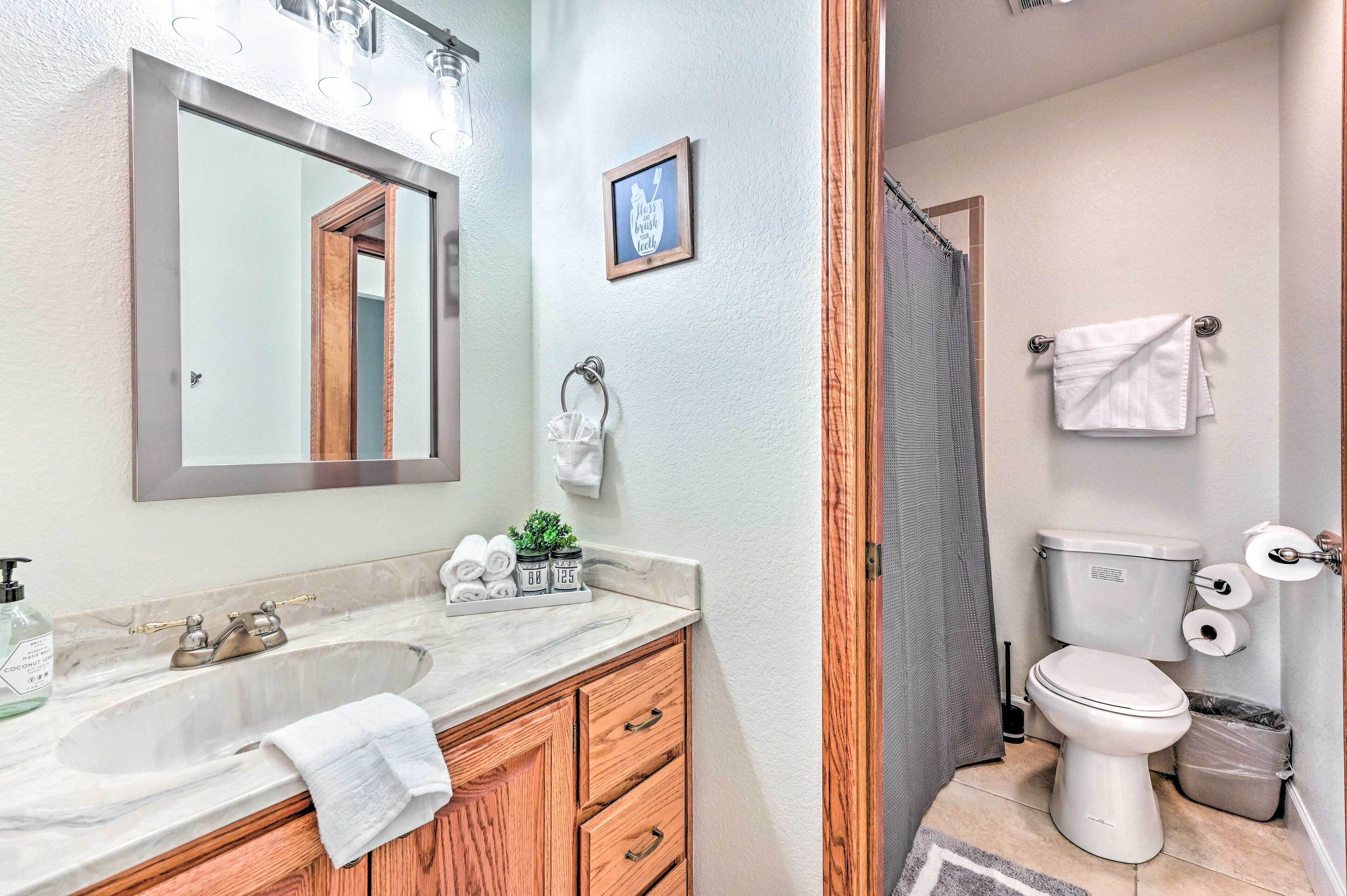 A bathroom with a sink, mirror, wooden vanity, towel rack, toilet, and shower curtain.