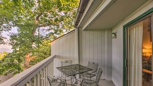 A covered outdoor patio with a table and chairs, a railing, and a view of trees and hills. - Slopeside Condo w/ Balcony & Ski Hill Views! (Nellysford)
