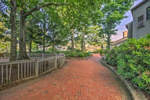 A brick pathway lined with trees and a fence, leading to a building with a light-colored exterior. - Slopeside Condo w/ Balcony & Ski Hill Views! (Nellysford)