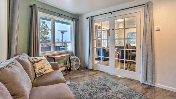 A cozy living room with a sofa, a fan, and a view of the outdoors through a sliding glass door.