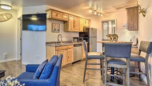 A modern kitchen with wooden cabinets, stainless steel appliances, and a dining area with a bear-themed table.