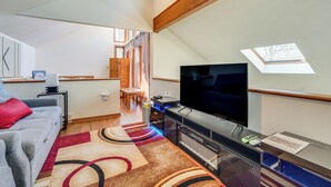 Una sala de estar moderna con un televisor de pantalla plana, un sofá, una mesa de centro y un comedor con una mesa y sillas.